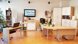 Modernes Büro mit hellen Holzmöbeln, Computern und freundlicher Arbeitsatmosphäre.